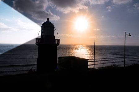 lighthouse captured with the sun behind it and beams onの写真素材
