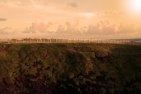 a man alone walking along the ballybunion cliff walk in ireland with a blazing sunの写真素材