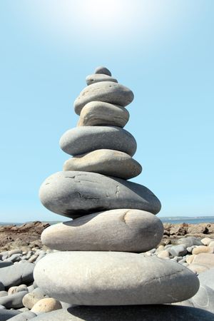 rocks balanced on a calm spiritual beach on the coast of ireland with a blazing sunの写真素材