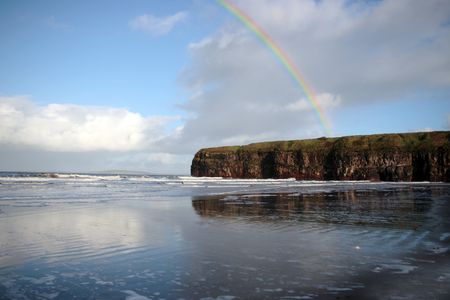 a view of the beach cliffs in ballybunion co kerry ireland with rainbow reflection on a wet stormy dayの写真素材