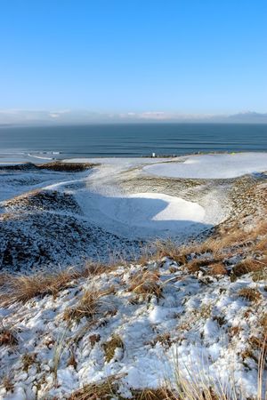 snow covered links golf course in ireland in winter with sea backgroundの写真素材