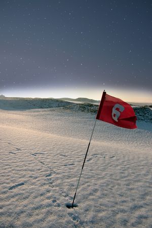 flag on a snow covered links golf course at night in ireland in winterの写真素材