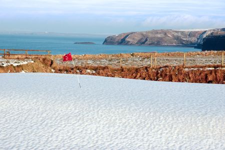 snow covering on a golf course in ireland in winter with sea and cliffs in backgroundの写真素材