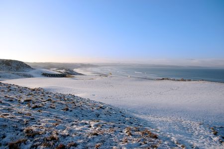 snow covered links golf course in ireland in winter with sea backgroundの写真素材