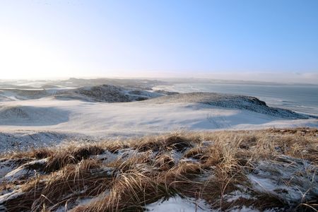 snow covered links golf course in ireland in winter with sea backgroundの写真素材