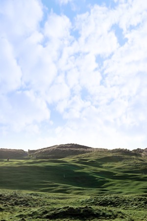 players and a flag waving on a hole on a links golf course in irelandの写真素材