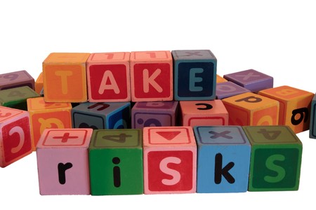 assorted childrens toy letter building blocks against a white background that spell take risksの写真素材