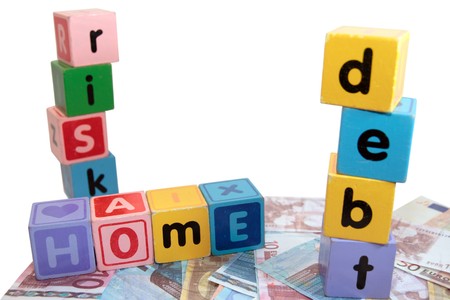 assorted childrens toy letter building blocks against a white background on money that spell home debt riskの写真素材