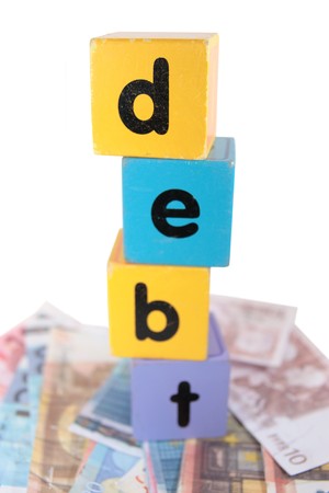 assorted childrens toy letter building blocks against a white background on money that spell debtの写真素材
