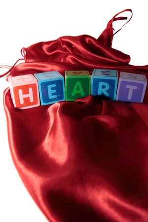 heart written with letter blocks on a silk nightie against white backgroundの写真素材