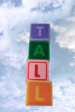 childrens toy letter building blocks against a cloudy background spelling tallの写真素材