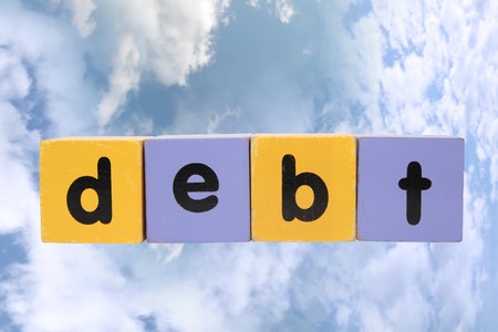 assorted childrens toy letter building blocks against a cloud background that spell debt の写真素材