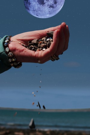 a hand full of earth against a beautiful blue moon in the starry night skyの写真素材