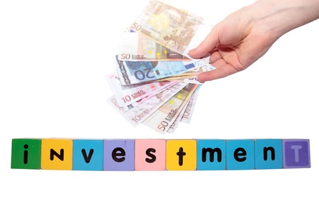 toy letters that spell house investment with cash in hand against a white background の写真素材