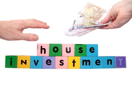 toy letters that spell house investment with cash in hands against a white background の写真素材