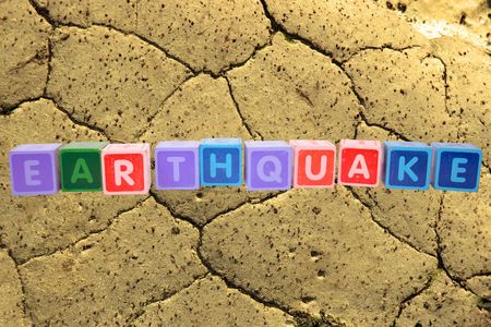 toy letters that spell earthquake against a barren land background の写真素材