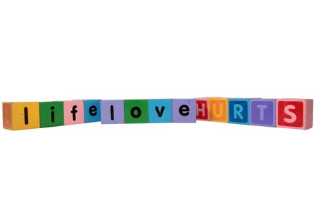 toy letters that spell life love hurts against a white background の写真素材