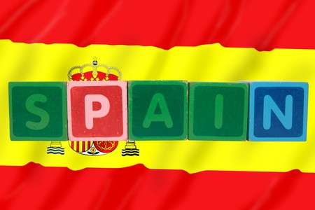 toy letters that spell spain against a flag background の写真素材