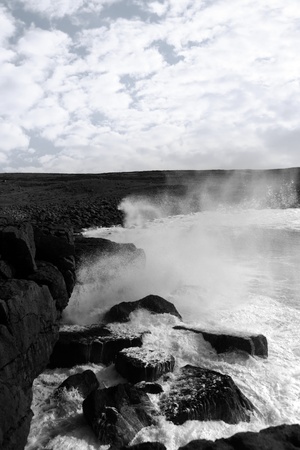 cliffs and coastline of the burren in county clare ireland with giant waves crashing on the rocks in black and whiteの写真素材