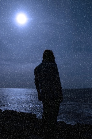 a lone woman looking sadly over the cliffs edge in county clare ireland during a rain stormの写真素材