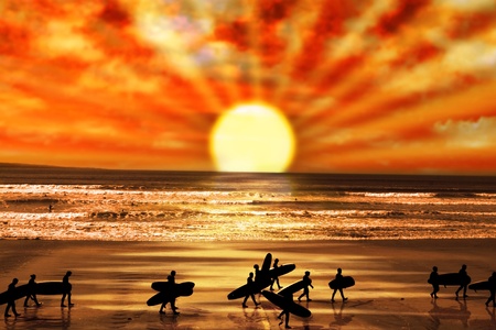surfers walking on the beach in lahinch county clare ireland as the sun goes down