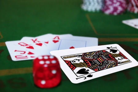 green casino table with dice and a hand of a royal flush in a poker game and the jack of spades in the packのeditorial素材