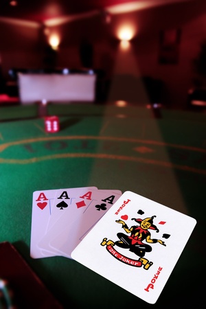 green casino table four aces in a poker game and a joker in the spotlightのeditorial素材