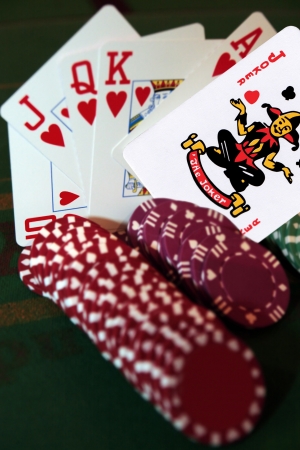 green casino table with chips and a hand of a royal flush in a poker game and a joker in the packのeditorial素材