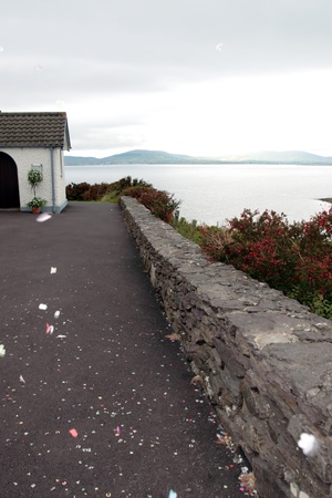 the exterior of an irish church with sea and mountain view and confetti in the air の写真素材