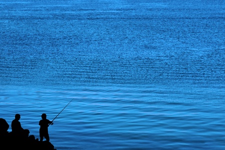 a silhouette of a father and son fishing of the rocks in irelandの写真素材