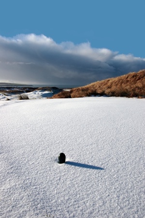 green tee on a snow covered links golf course in ireland in winterの写真素材