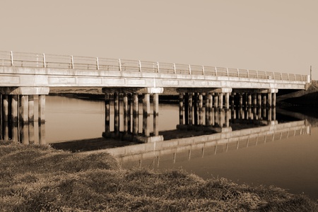 bridge over a calm cold river in kerry ireland on a frosty morning in sepiaの写真素材
