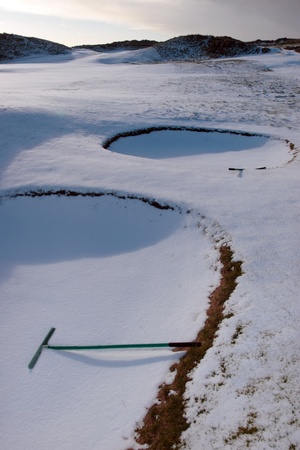 rakes in bunkers on a snow covered links golf course in ireland in snowy winter weatherの写真素材