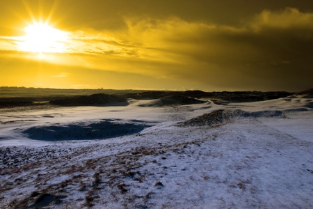  bunkers on a snow covered links golf course in ireland at sundown in snowy winter weatherの写真素材