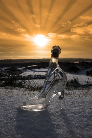 a crystal glass slipper in a snow covered irish golf course at sunset for a concept on ladies golfの写真素材
