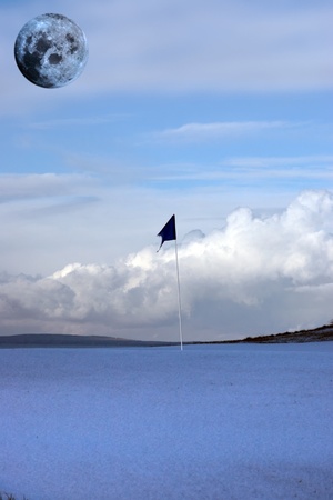 a snow covered links golf hole in ireland with blue flag and full moon in skyの写真素材