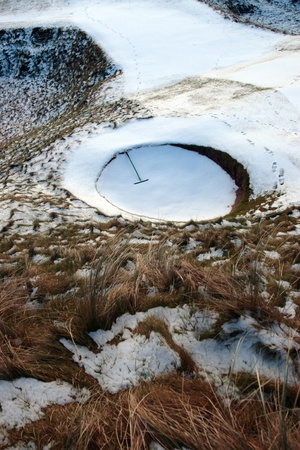 a rake in a bunker on a snow covered links golf course in ireland in snowy winter weatherの写真素材