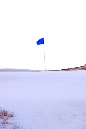 a snow covered links golf hole in ireland in winter weather with blue flagの写真素材