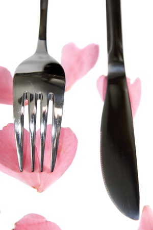 fork and knife isolated with rose petals for concept on romantic diningの写真素材