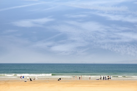 sandy golden beach with surfers and children running into the sea to surf in ballybunion county Kerry Irelandの写真素材