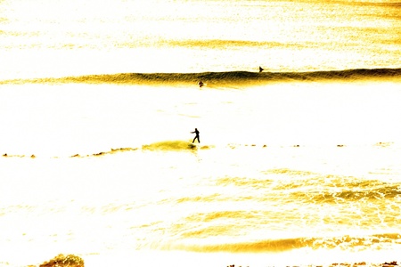 golden sea with people surfers catching the wavesの写真素材
