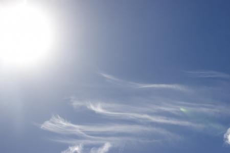 white fluffy clouds and trails against lovely blue sky with bright sun shineの写真素材
