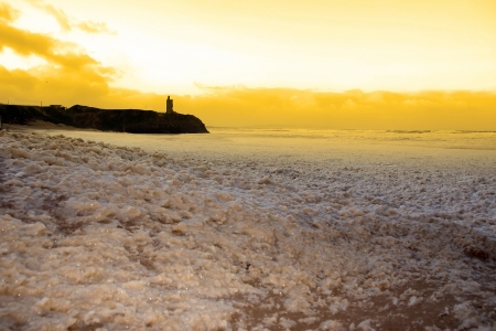 sweeping waves of foam crashing against Ballybunion beach on a dark sunset evening during a storm of the west coast of irelandの写真素材