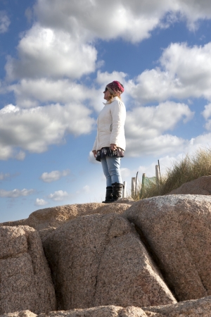 woman looking out to sea at the top of old natural rock formation on a beach in county Donegal, Irelandの写真素材