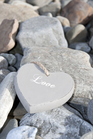 single inscribed grey wooden love heart on a pebble beach in Irelandの写真素材