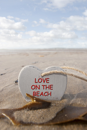 single wooden love heart in the sand on a wild Atlantic way Irish beach in summer with copy spaceの写真素材