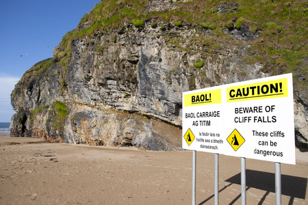 beware of land falls warning sign beside the cliffs in Ballybunion county Kerry Ireland in English and Gaelicの写真素材