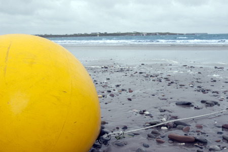 giant yellow buoy on a beach in the wild atlantic wayの写真素材