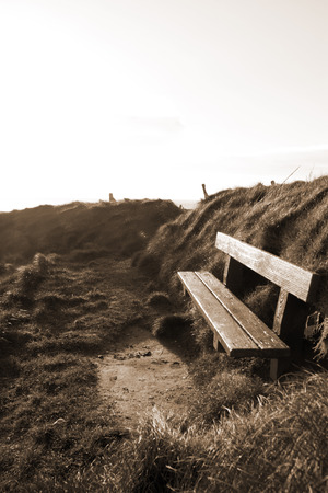bench on a cliff  with views of Ballybunion beach and coast at sunset in sepiaの写真素材