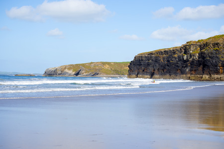 bright winter view of kayaker at ballybunion beach and cliffs on the wild atlantic way in irelandの写真素材